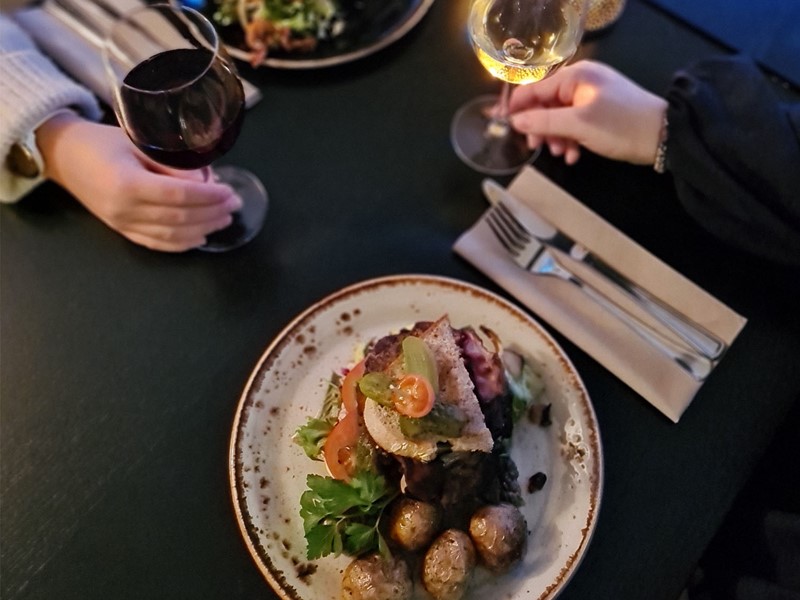 To hender som holder vinglass, to tallerkener med mat