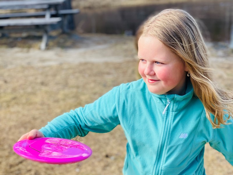 Jente koser seg med frisbeegolf